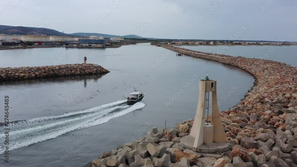 Boat entering a canal aerial drone shot lighthouse and breakwater along France Sete Frontignan Boat entering a canal aerial drone shot lighthouse and breakwater along France Sete Frontignan