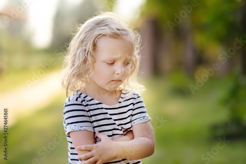 Upset or offended little girl standing on street of small town's or village's. Сrisis of three years.