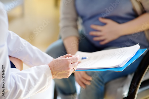 Pregnant woman sign the contract or permit during accepts of gynecologist doctor. Medical insurance childbearing. Family doctor for gestation. Maternity leave.