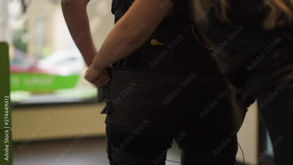 MCU: Trainer attaches EMS Vest to clients buttocks in preparation for Electrical Muscular Stimulation Excercises MCU: Trainer attaches EMS Vest to clients buttocks in preparation for Electrical Muscular Stimulation Excercises