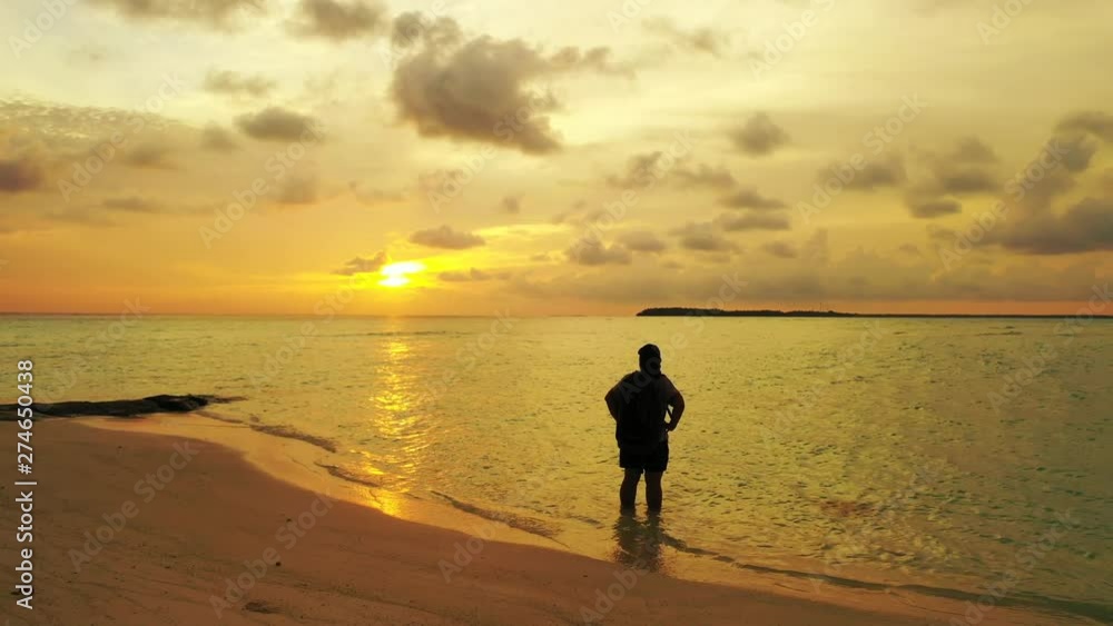 tourist with backpack standing till knees in tropical sea water and admiring tranquil golden sunset tourist with backpack standing till knees in tropical sea water and admiring tranquil golden sunset