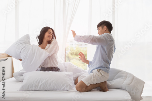 Asian couple sits on bed, They have pillow fight.. © Bangkok Click Studio