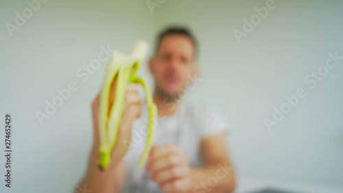 Man in defocussed background peels and eats foreground bananna. Locked off photo