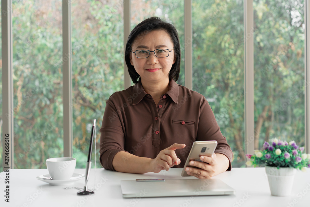 Obraz premium confident elderly asia woman using pad and laptop for business