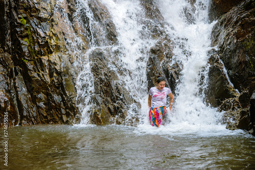 Fototapeta Naklejka Na Ścianę i Meble -  Girl traveling waterfall on holiday. The girl who is enjoying playing the waterfall happily. travel nature, Travel relax, travel Thailand. Huai Toh waterfall at Krabi.