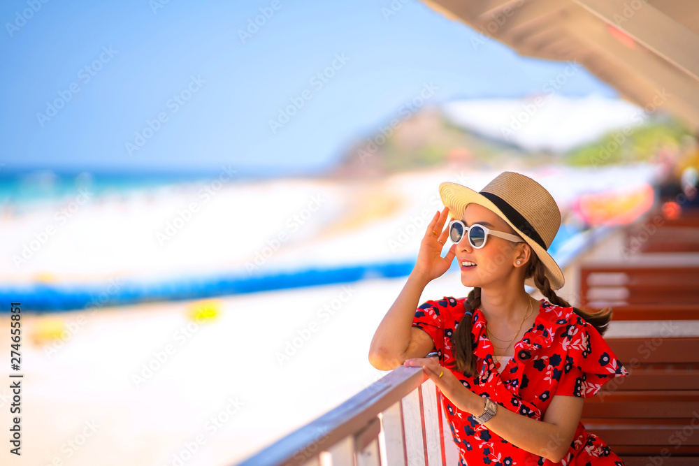 traveler girl in red dress wearing sunglasses and hat posing relax in outdoor with sunlight in the sea traveler girl in red dress wearing sunglasses and hat posing relax in outdoor with sunlight in the sea