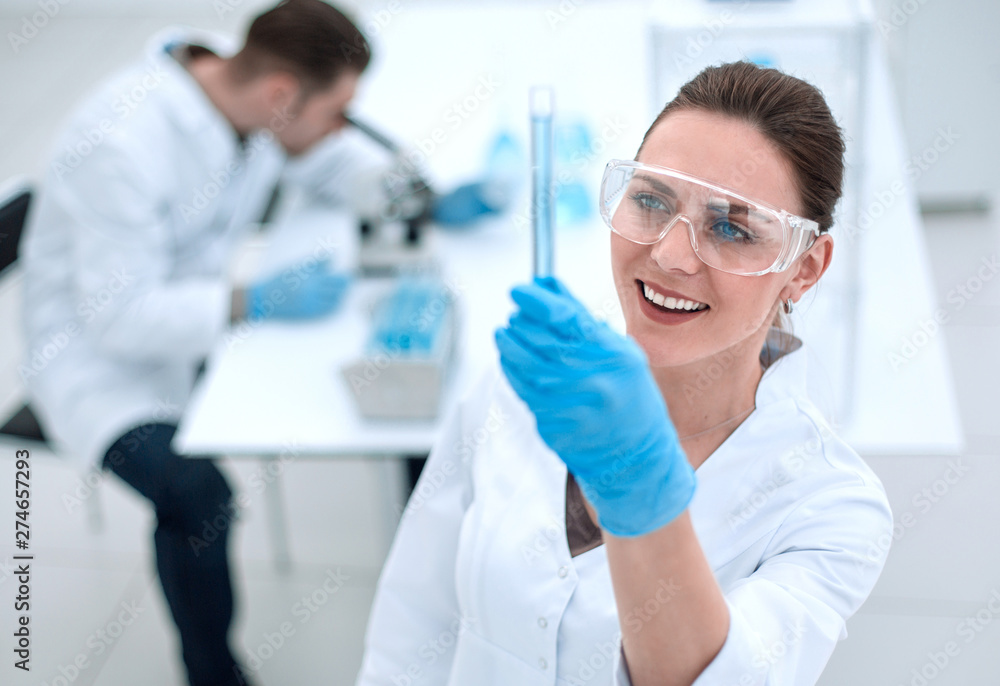 smiling woman scientist looking at the tube with the results of the analysis smiling woman scientist looking at the tube with the results of the analysis