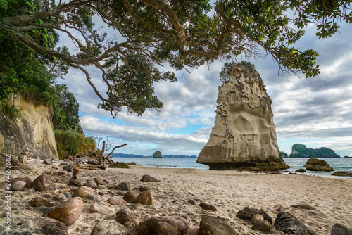sandstone rock monolith behind stones in the sand at cathedral cove, new zealand 15