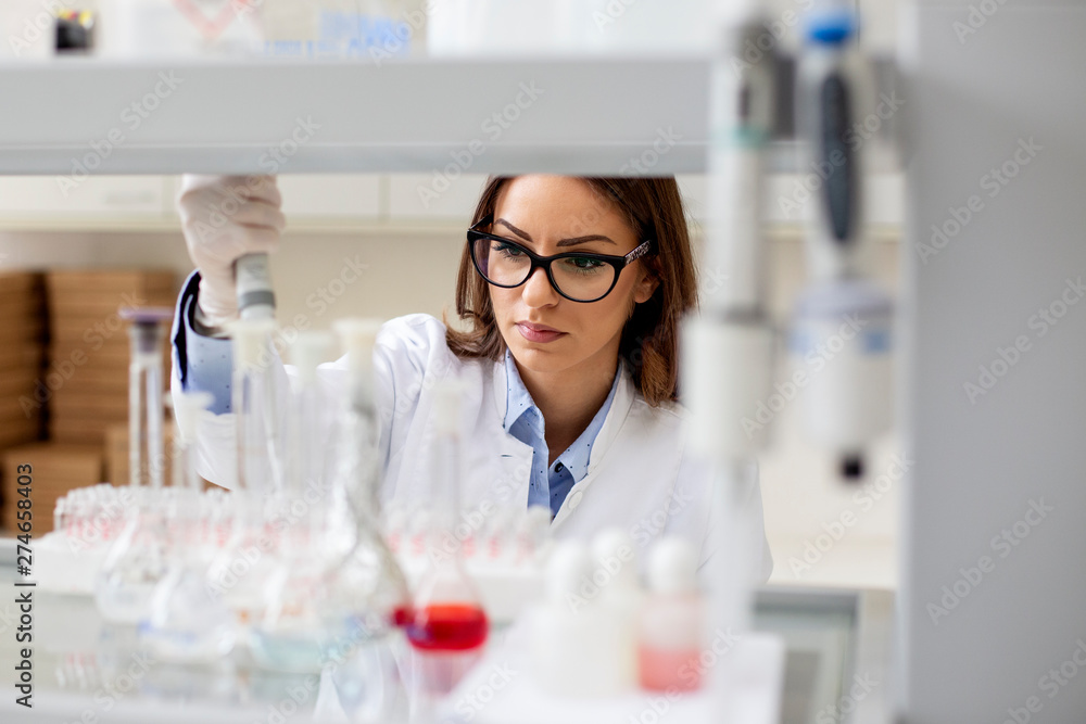 Young woman working in laboratory on some experiment Young woman working in laboratory on some experiment