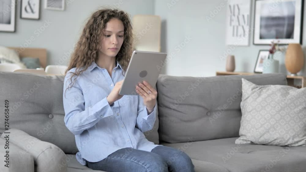 Online Shopping on Tablet by Curly Hair Woman Sitting on Couch Online Shopping on Tablet by Curly Hair Woman Sitting on Couch