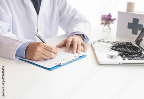 Close up male doctor or medical student using mobile smart phone working on laptop computer in hospital with copy space.