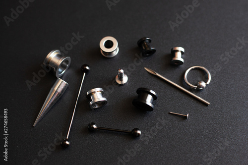 Diverse set for piercing on a dark background, ear tunnels, tunnels and earrings for the ears and tongue close-up