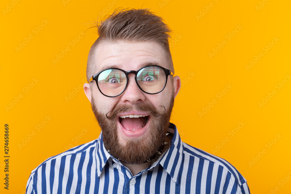 Stylish young hipster man with a mustache and beard joyfully opens his mouth on a yellow background. Concept of surprise and celebration. Copyspace. Stylish young hipster man with a mustache and beard joyfully opens his mouth on a yellow background. Concept of surprise and celebration. Copyspace.