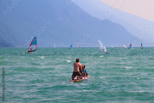Father and kids enjoying paddling on SUP (Stand up paddling) board at Lake Garda (Torbole, Italy)