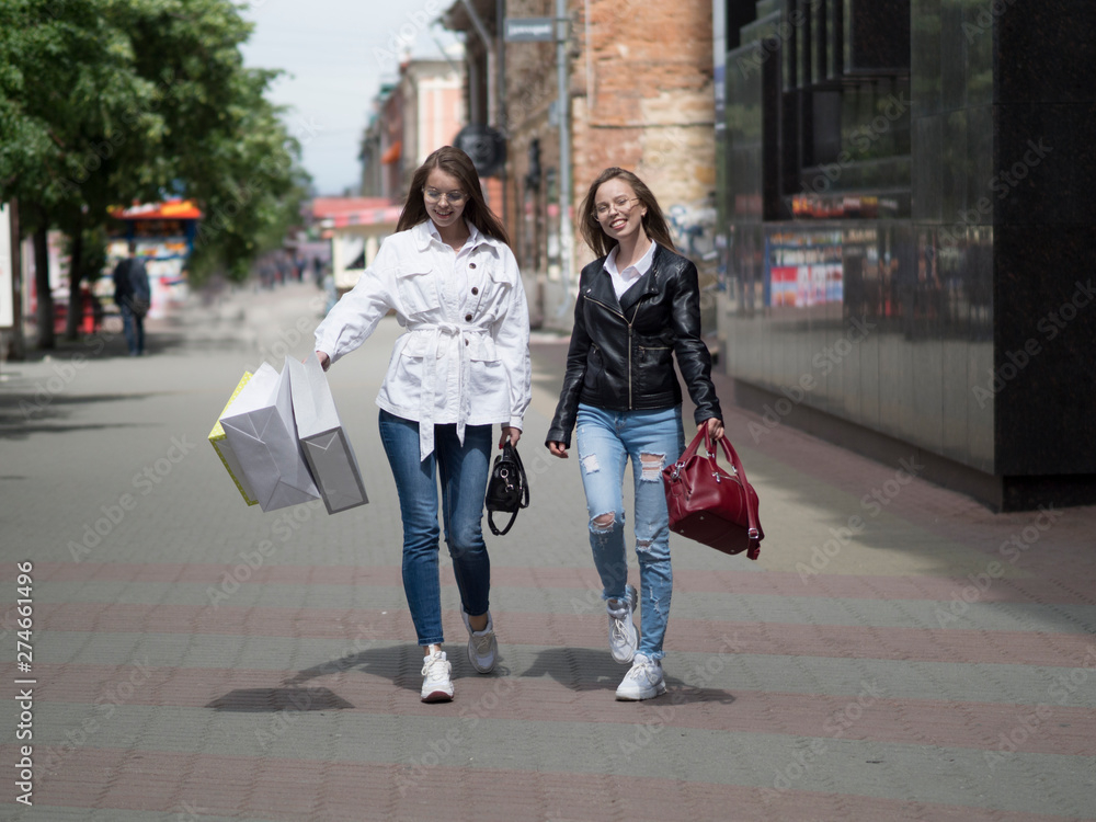 Young Women with Shopping Bags Walking City Street. Sale, Consumerism and People Concept