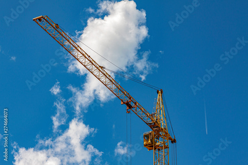 Construction crane against the blue sky with clouds.