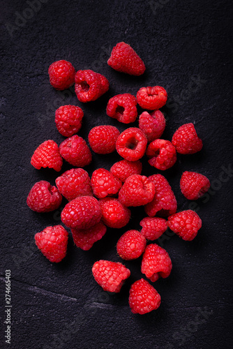 top view, on a black and rustic background, some fresh raspberries.