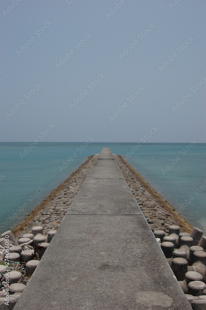 南国沖縄のエメラルドグリーンの海の防波堤