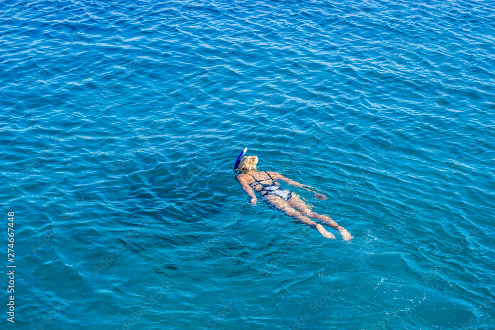 sexy woman enjoy by swimming and snorkeling in Red sea water natural environment, aerial photography form drone above vivid blue smooth water surface background with empty space for copy or text