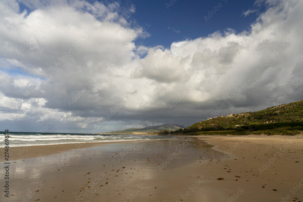 Deep Atlantic Ocean water colors, breaking waves in a sandy beach, spectacular clouds in the sky. Romantic Spring Morning at Bologna Beach, Tarifa, Cadiz, Andalusia, Spain, Europa. Deep Atlantic Ocean water colors, breaking waves in a sandy beach, spectacular clouds in the sky. Romantic Spring Morning at Bologna Beach, Tarifa, Cadiz, Andalusia, Spain, Europa.
