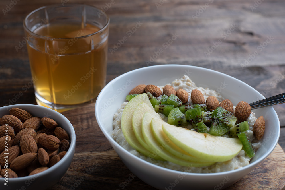 healthy breakfast. oatmeal with green Apple, kiwi, and almonds with dried fruit compote