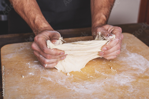 Closeup of male hands knead the dough for homemade pizza, the problems of cooking, an incompetent chef