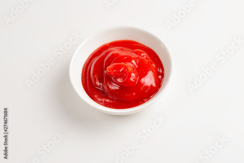 Ketchup in white plate on white background.