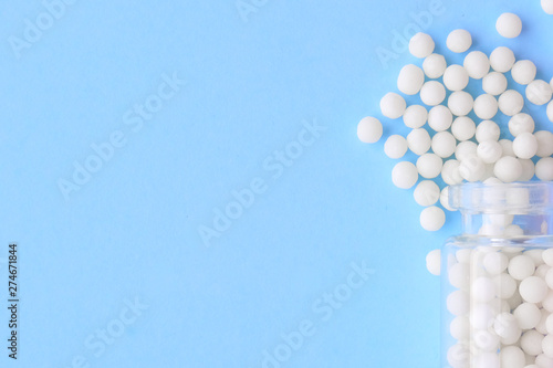Close up homeopathic globules and glass bottle on blue background. Alternative Homeopathy medicine herbs, healtcare and pills concept. Flatlay. Top view. copyspace for text