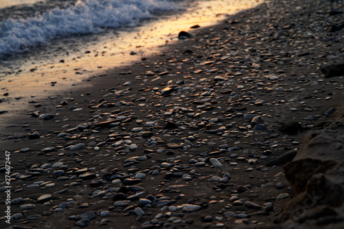 A strip of sunlight among the pebbles on the sandy seashore.