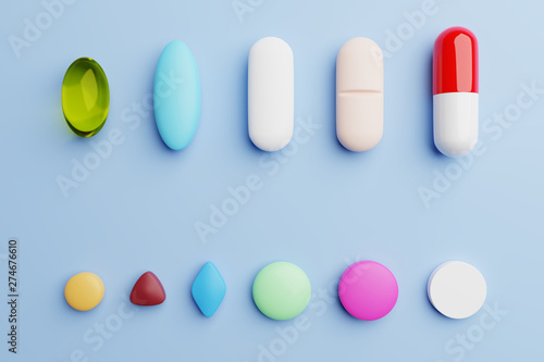 Pills of different shapes and colors on blue background