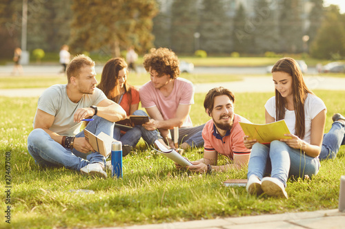 A group of students studying books sitting in a city park.