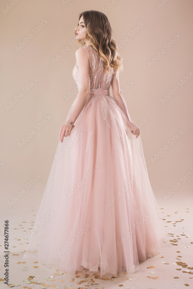 Beautiful girl in evening elegant dress posing on paper beige studio background full length portrait Beautiful girl in evening elegant dress posing on paper beige studio background full length portrait