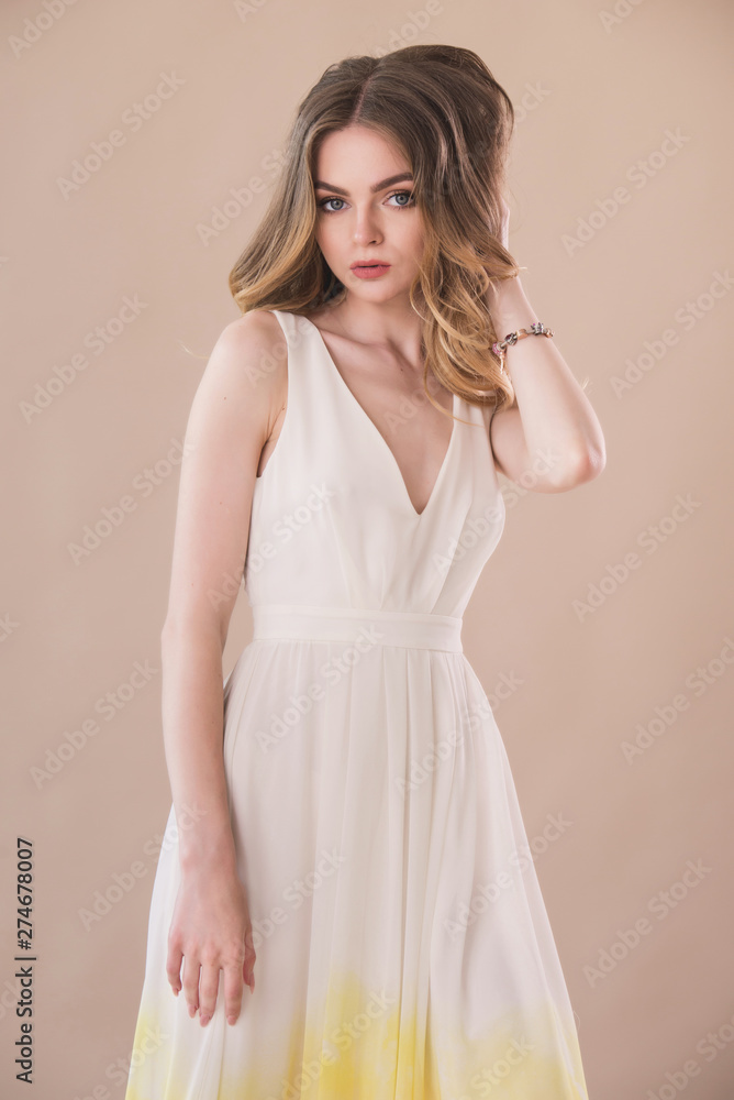 Beautiful woman portrait in elegant dress on beige background