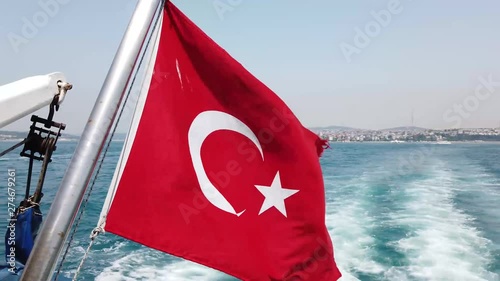 View of the Turkish flag on the boat in Istanbul Bosphorus for traveler to sightseeing with the beautiful wave and cityscape in the background in Turkey.