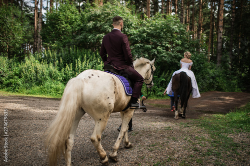 Bride and groom ride on horses.