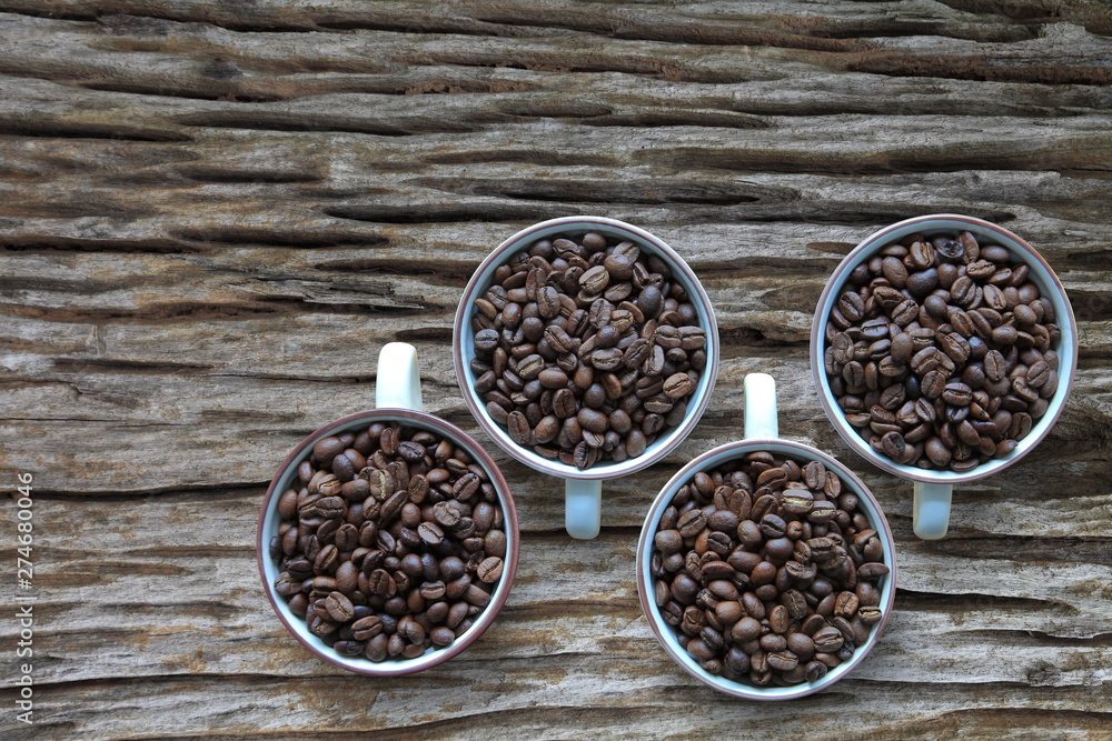 Full cup of heap coffee bean on aged rustic wooden table with copy space from top view Full cup of heap coffee bean on aged rustic wooden table with copy space from top view