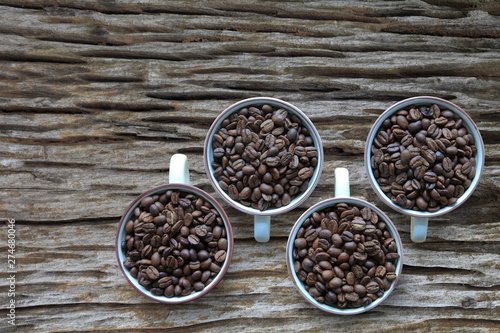 Full cup of heap coffee bean on aged rustic wooden table with copy space from top view 