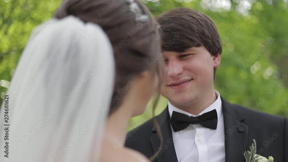 Handsome groom hug his beautiful bride. Newlyweds walking in the park. Brown hair woman in elegant wedding dress. Blossom tree Handsome groom hug his beautiful bride. Newlyweds walking in the park. Brown hair woman in elegant wedding dress. Blossom tree
