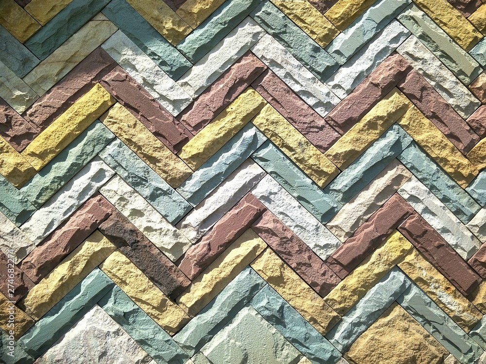 Close up abstract horizontal zigzag pattern of the old multicolored sandstone tiles wall background in vintage style, exterior architecture concept