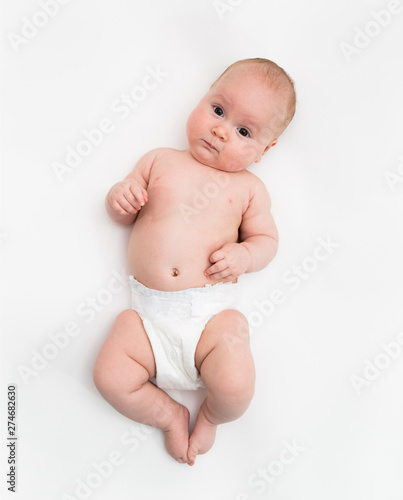 A cute four month old baby girl wearing a white diaper cover lie down on white background.