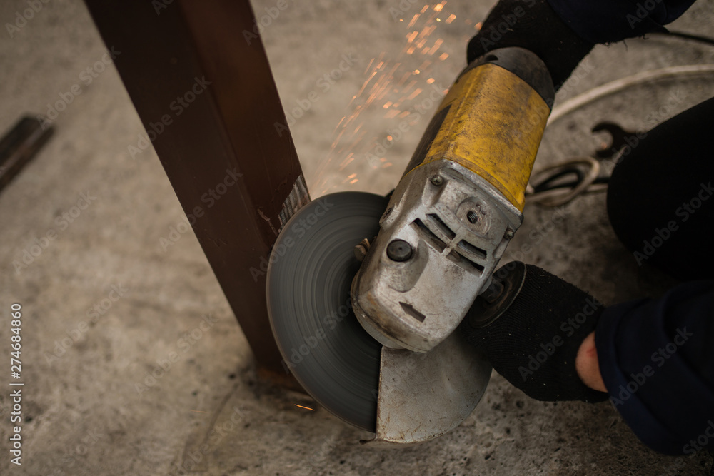 Worker in overalls and a protective mask cuts metal apparatus. The profession of welder. The man in overalls. worker cutting metal with a saw. grinder.