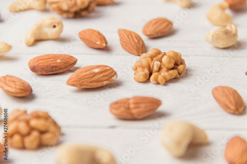 Assortment of nuts on white wooden table. Cashew, hazelnuts, walnuts, almonds.