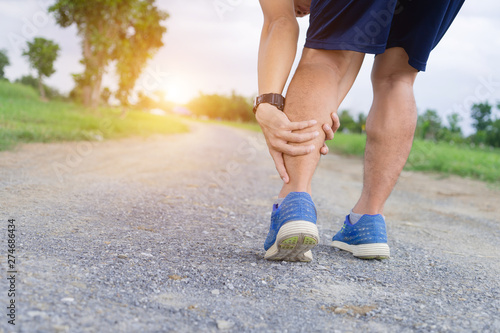 Runner sportsman holding leg in pain after suffering muscle injury during running workout training.