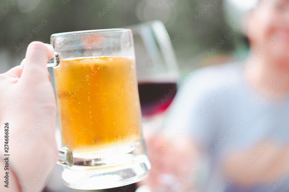 hand holding beer mug smash with wine glass at restaurant, selective focus hand holding beer mug smash with wine glass at restaurant, selective focus