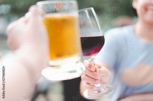 blurred hand holding beer mug smash with wine glass at restaurant  selective focus