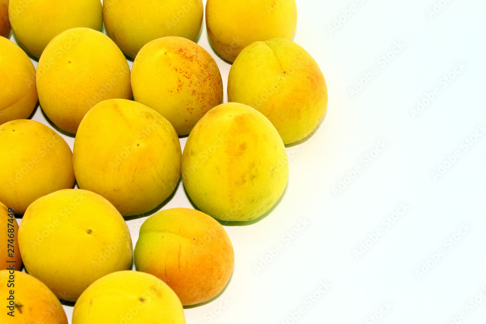 Small yellow apricots lie on a white background Small yellow apricots lie on a white background