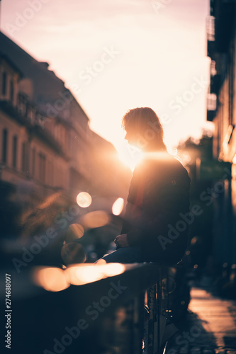 Silhouette Junger Mann sitzt auf Geländer bei Sonnenuntergang in Straße