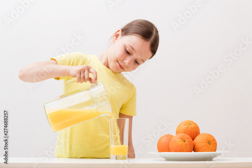 child pours orange juice into a glass