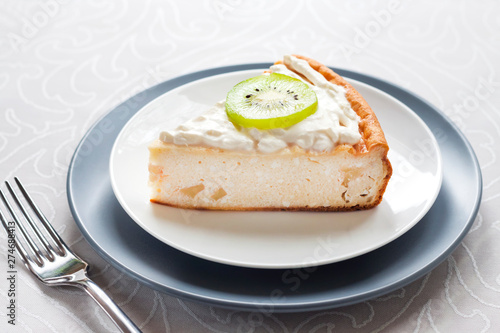 Homemade cottage cheese cake with kiwi fruit and cream on a plate