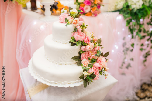 the bride and groom cut the beautiful white wedding cake with fresh flowers